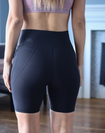 Back view of active mother wearing high waisted postpartum bike shorts