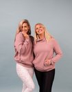 Two happy mothers both wearing a pink breastfeeding hoodie