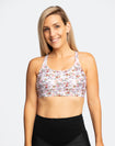 front view of fit, active mum wearing cadenshae white floral print crossover back nursing bra